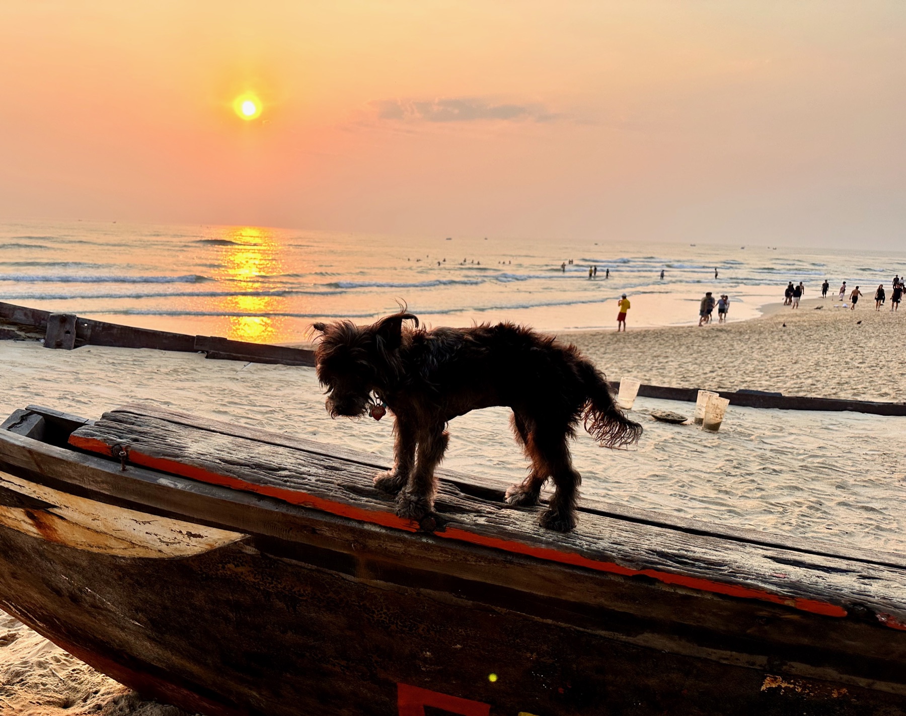 Lucie standing on a wooden beach boat as the sun rises over My An Beach in Da Nang